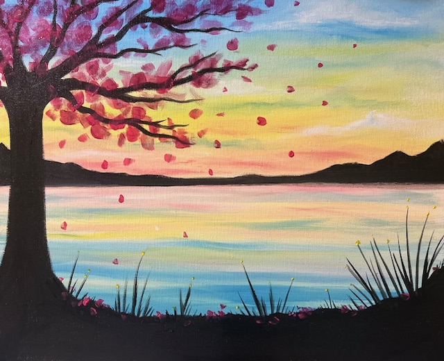 Cherry blossom tree by colorful lakeside sunset