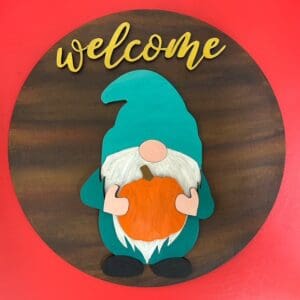 Wooden gnome holding pumpkin with welcome sign.